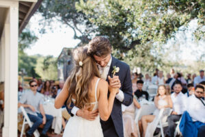 A bride and groom dancing while holding each other close in the center of a blurred out dance floor.